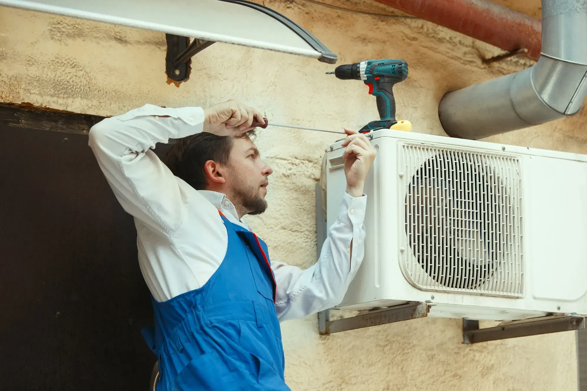 Accolade Heating TECA-certified technician inspecting an AC system in a Surrey BC home
